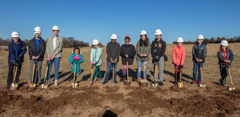 students pose with shovels at construction site for new high school