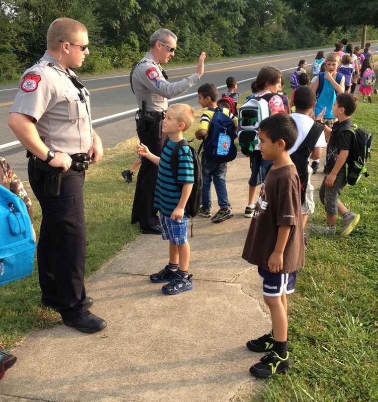 students chatting with and giving high five to police officers