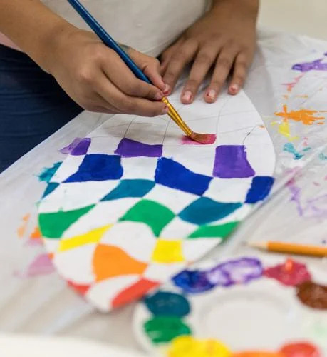 A student paints a leaf for the mural